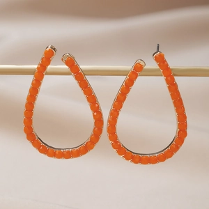 Orecchini a goccia dorati con perline arancioni su un elegante supporto da esposizione