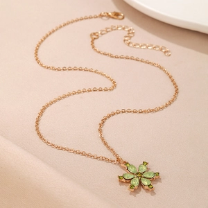 Detail of rose gold flower pendant with green gemstones on beige silk fabric