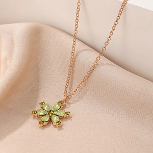 Elegant rose gold floral necklace with green gemstones and diamonds on silk background