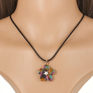 Macro shot of five-petal floral pendant with mottled texture and black cord necklace