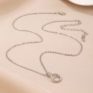 Close-up of sparkling silver-tone necklace featuring a crystal-encrusted circular pendant