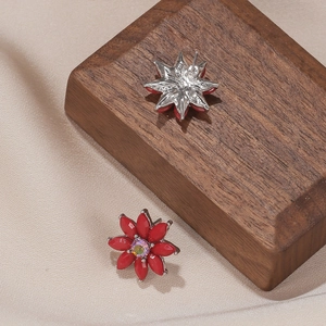 Détail de boucles d'oreilles fleurs rouges avec cristal scintillant sur fond soie