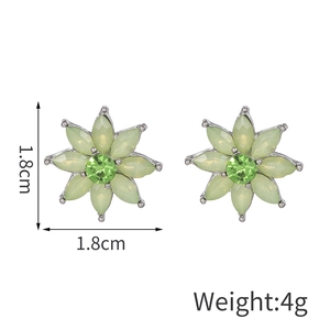Vue détaillée des boucles d'oreilles fleurs avec gemmes vertes et centre en cristal