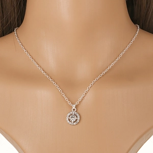 Close-up of sparkling silver cluster pendant with central diamond and halo on a mannequin