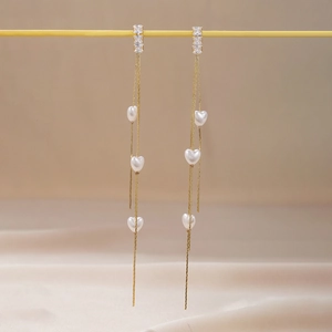 Détail de boucles d'oreilles pendantes avec cristaux et perles en forme de cœur