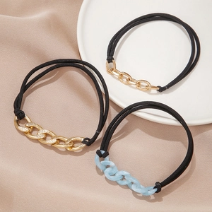 Three-piece set of gold and blue chain elastic hair ties on a satin display background