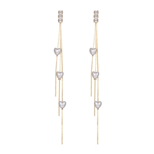 Détail de boucles d'oreilles à pampilles dorées avec zircons et perles cœurs