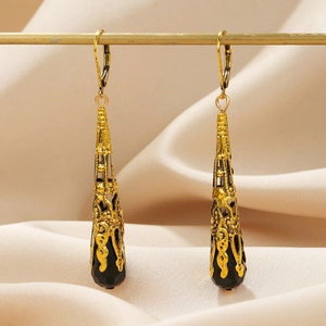 Detail van vintage lange oorbellen met gouden filigraan en zwart gefacetteerde druppelhanger