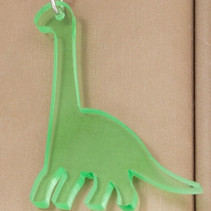 Macro detail of translucent green dinosaur acrylic earring with polished silver metal ring