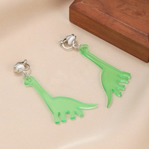 Detail of green acrylic dinosaur clip-on earrings on a warm beige fabric background
