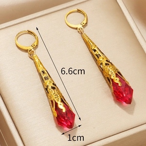 Macro-opname van vintage gouden druppeloorbellen met rode kristallen en hol patroon