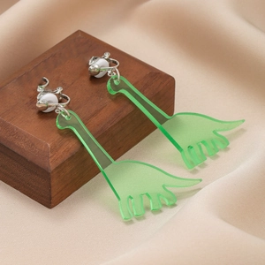 Macro detail of green acrylic dinosaur clip-on earrings with soft white silicone pads