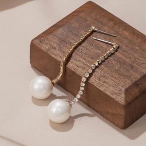 Détails de boucles d'oreilles dorées avec glands en diamant et grandes perles