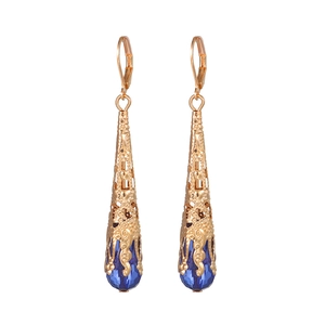 Detailopname van vintage gouden filigraan oorbellen met blauwe traanvormige kristallen
