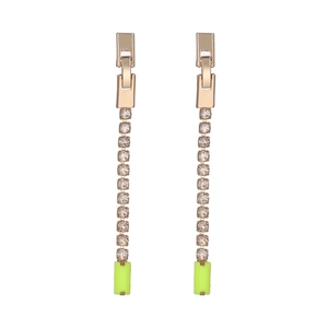 Détail de boucles d'oreilles dorées avec cristaux et pierres vert néon