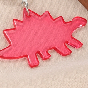 Macro detail of a vibrant translucent rose red acrylic dinosaur earring with metal ring