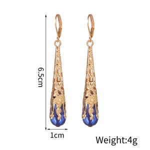 Detailopname van goudkleurige legering oorbellen met blauw kristal, 6,5 cm lang en 4g zwaar