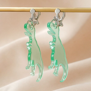 Macro view of transparent green acrylic dinosaur clip-on earrings on a silk background