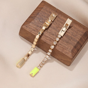 Détail de longues boucles d'oreilles dorées à glands avec strass et touches jaune néon