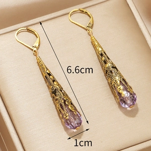 Gedetailleerde weergave van gouden oorbellen met paarse druppelkristallen van 6,6 cm