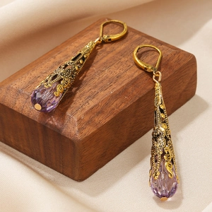 Detail van vintage gouden oorbellen met paarse kristallen op elegante zijden achtergrond