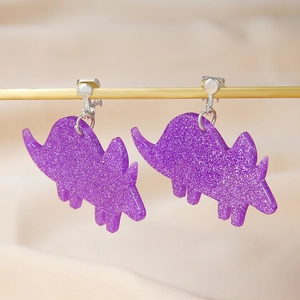 Detail of purple glitter acrylic dinosaur earrings with shimmering sequins and silver hooks