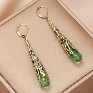 Macro-opname van vintage druppeloorbellen met groen kristal en gouden hefboomsluiting