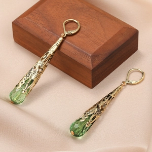 Detail van vintage druppeloorbellen met groene kristallen en goudkleurig filigraan