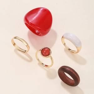 Five-piece ring set with red resin, wood grain, and gold metal bands on beige background