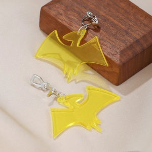 Macro detail of yellow acrylic bird-shaped clip-on earrings on wooden block and fabric