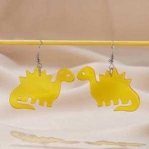 Detail view of yellow acrylic dinosaur earrings with silver hooks on a soft fabric backdrop