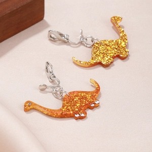 Detail of sparkly dinosaur clip-on earrings with glitter resin in yellow and orange