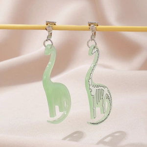 Detail view of light green dinosaur ear clips with fossil skeleton print on pink fabric