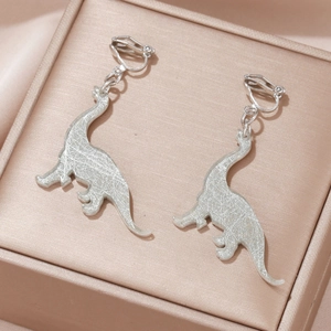 Macro detail of silver dinosaur ear clips with unique cracked texture on a jewelry box
