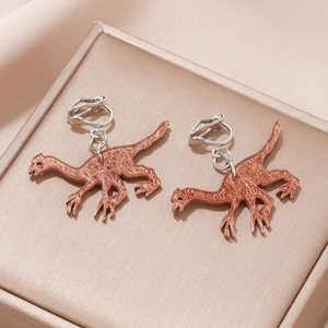 Detail of copper dinosaur clip-on earrings with brushed metal texture and silver clip