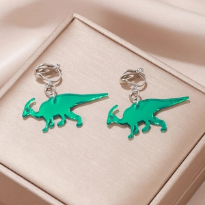 Detail of green acrylic dinosaur ear clips on a silk fabric inside a jewelry box