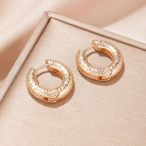 Elegante goldene runde Creolen mit Hammerschlag-Textur in einer luxuriösen Schmuckschatulle