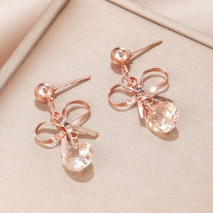 Detail of rose gold bow earrings with champagne zircon tassels on a premium jewelry box