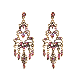 Detailopname van vintage goudkleurige oorbellen met roze strass en holle decoraties