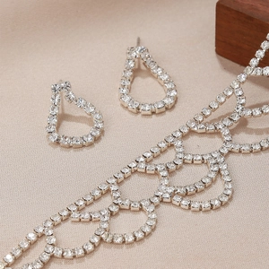 Elegantes Set aus Strass-Halskette und Wassertropfen-Ohrringen auf strukturiertem Stoff