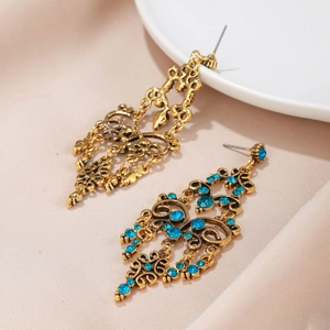 Detail van vintage gouden oorbellen met blauwe steentjes op zijde en een porselein