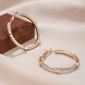 Macro detail of gold hoop earrings with sparkling rhinestones and star accents