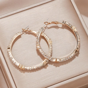 Elegant gold hoop earrings with sparkling rhinestones and star charms on silk background
