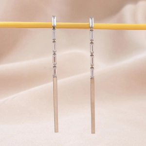 Macro view of long silver drop earrings featuring clear zircon stones and metal bar