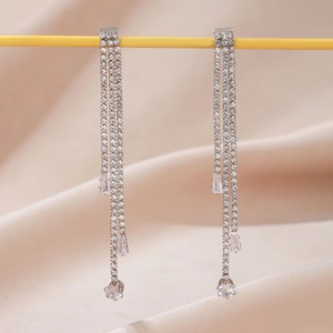 Close-up of elegant long tassel earrings with sparkling rhinestones and drop-shaped zircon