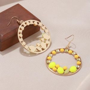 Détail de boucles d'oreilles bohèmes rondes avec perles jaunes et paillettes arc-en-ciel