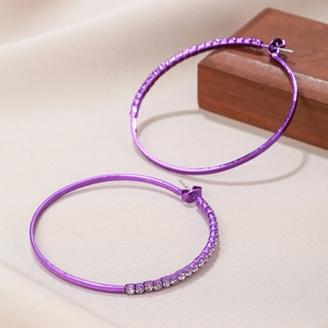 Macro detail of purple hoop earrings with sparkling zircon inlay and polished finish