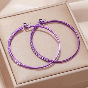 Detail of purple hoop earrings with sparkling rhinestones on a gold jewelry box