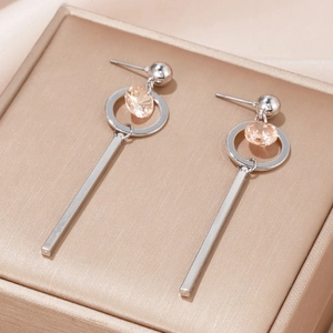 Macro view of long silver tassel earrings with champagne zircon on golden jewelry box