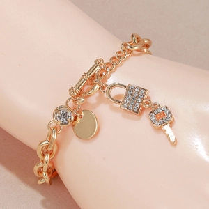 Detail of gold alloy bracelet with crystal charms, lock and key pendant on a wrist